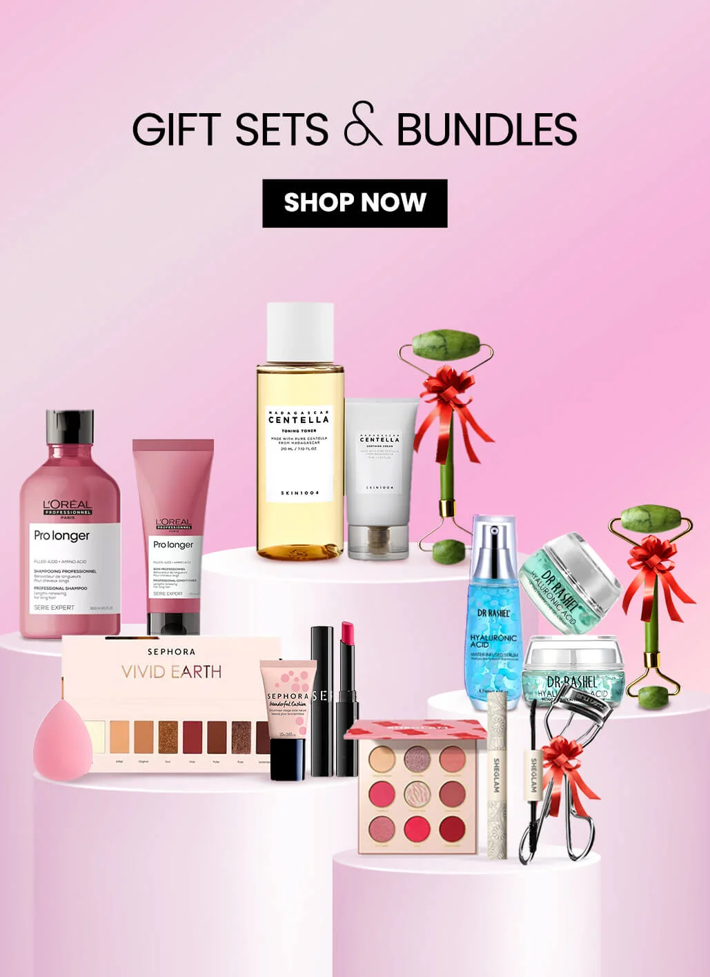 Beauty and skincare gift sets displayed on white podiums against a pink background. Includes L'Oréal shampoo, Centella toner, Dr. Rashel hyaluronic acid, Sephora makeup, and jade rollers with red bows. 